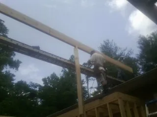 Carpenter setting a ridge beam over a new addition frame — Ice Dam Removal by Roofing Brothers in Cable