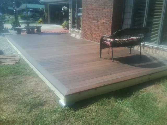 New wood deck and wicker chair beside a brick house in Cable